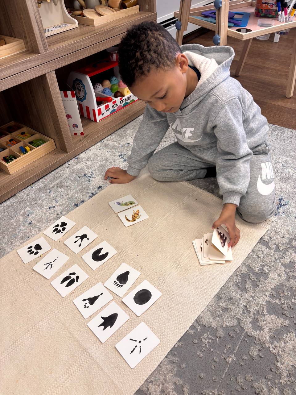 A young child matching animal track cards on a mat at Elements Workspace.